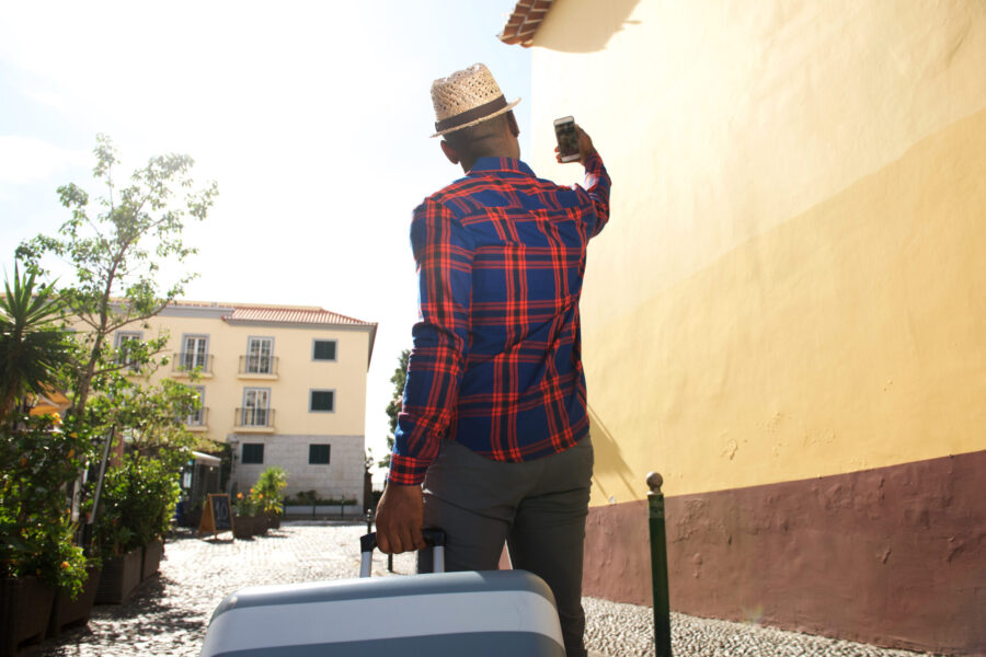 Portrait from behind of black traveling man taking selfie with mobile phone